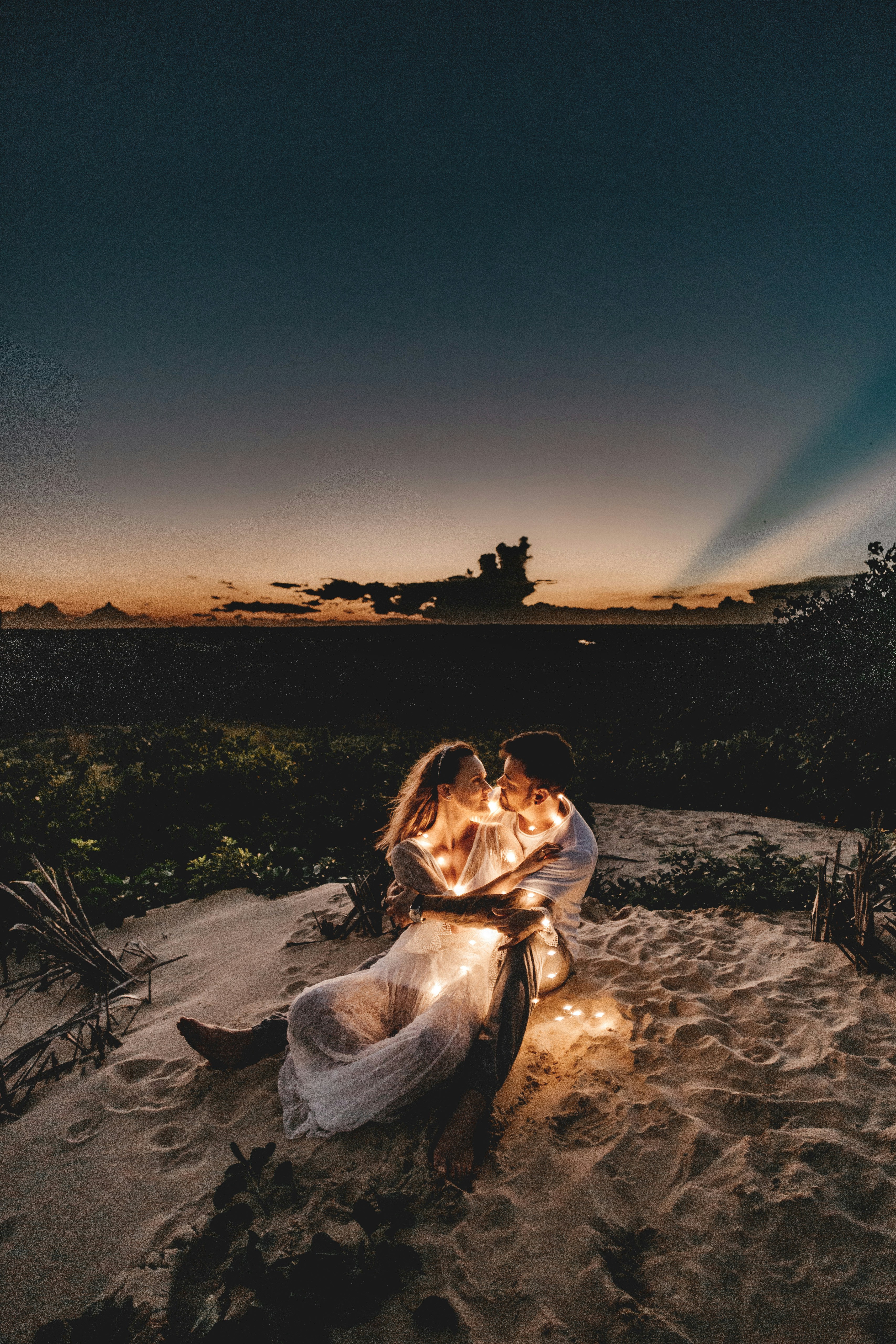 great photo recipe,how to photograph man and woman looking each other sitting on white sand during sunset