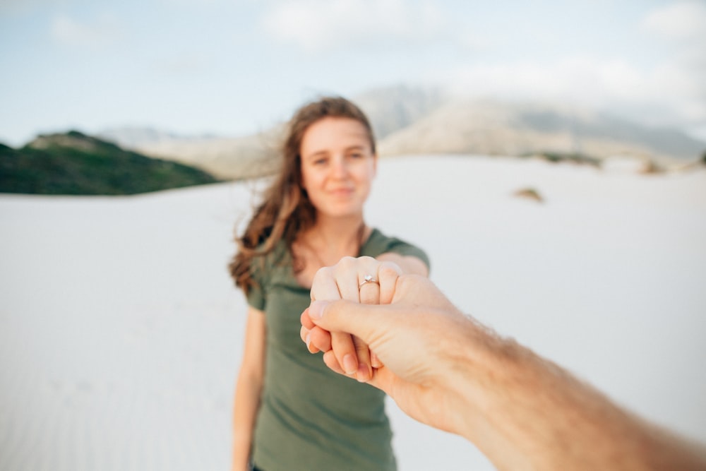 woman wearing green top holding hand