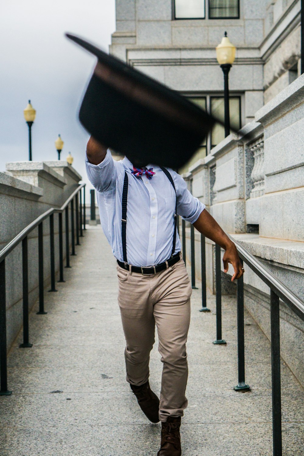 man throwing hat towards camera covering his face