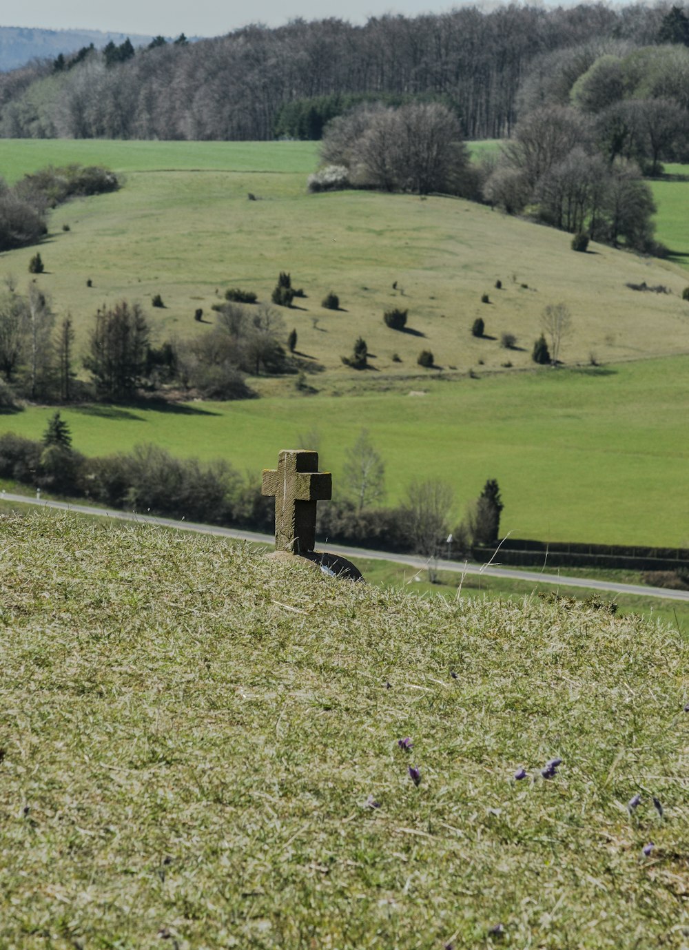 concrete cross standing on green grass field