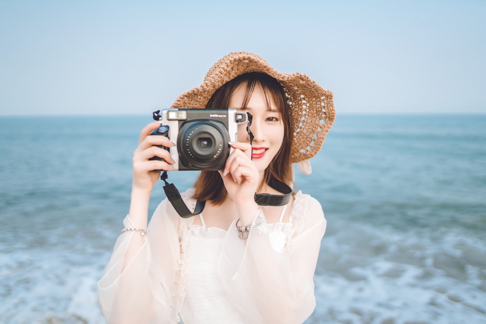 donna che tiene la macchina fotografica alla spiaggia