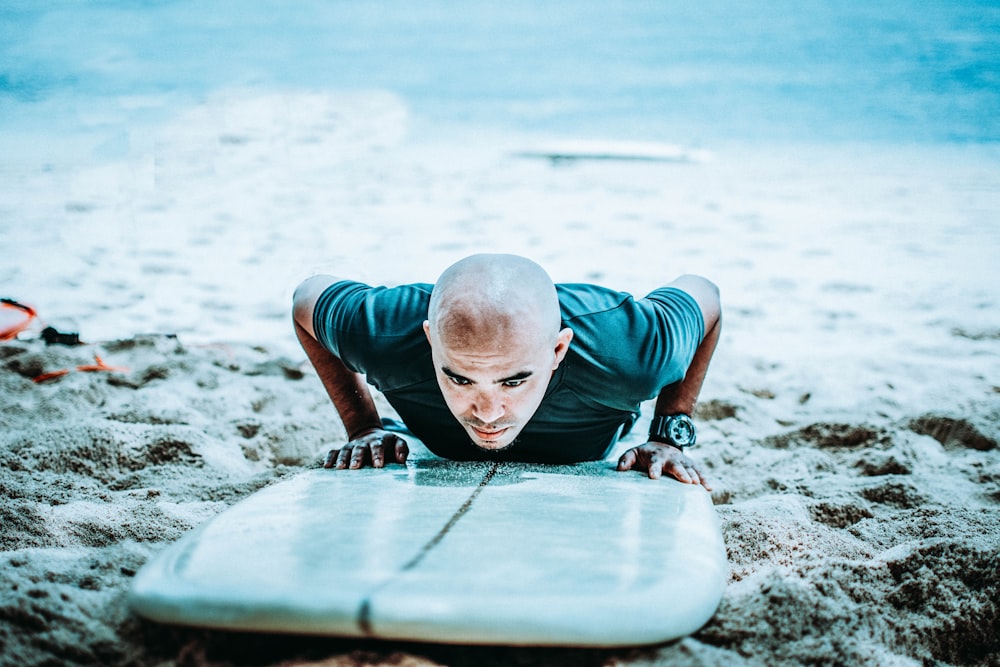 man above white surfboard in beach