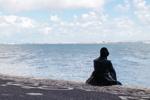 person sitting on concrete seawall