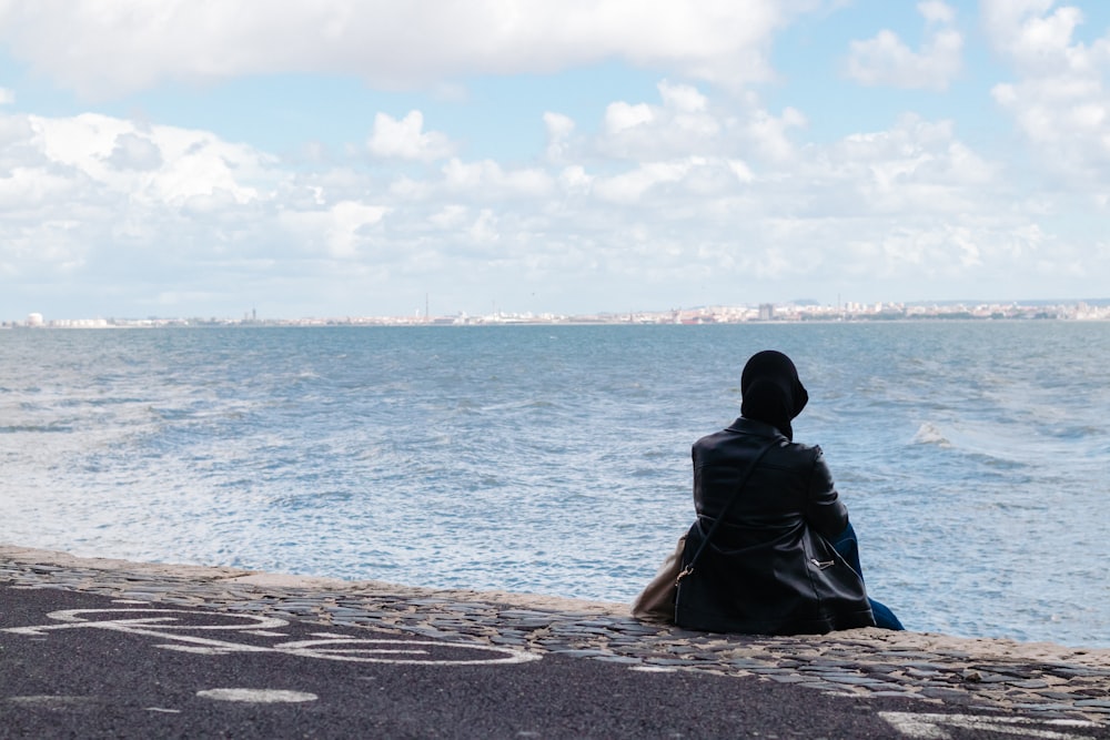 person sitting on concrete seawall