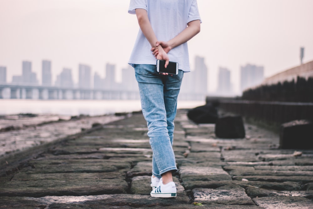 person wearing jeans and holding phone