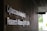 Signage on a wall reads 'Cybercrime Analysis & Research Alliance @ NTU (CARA)' in bold, white letters against a dark, textured surface. A corridor with partial ceiling panels is visible, and there's some greenery in the background.
