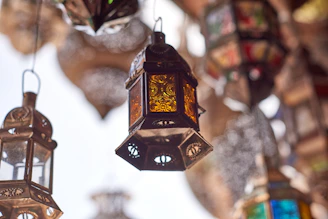 A close-up of intricately crafted brass lanterns glowing warmly against a rustic wooden backdrop.