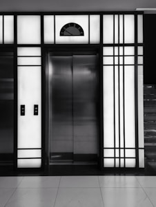 Technician carefully installing a modern elevator inside a commercial building lobby.