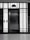 A modern elevator is centered between illuminated panels with a minimalist, geometric design. The elevator doors are metallic and closed, with control buttons on either side. Above the doors, a display shows the number 3.