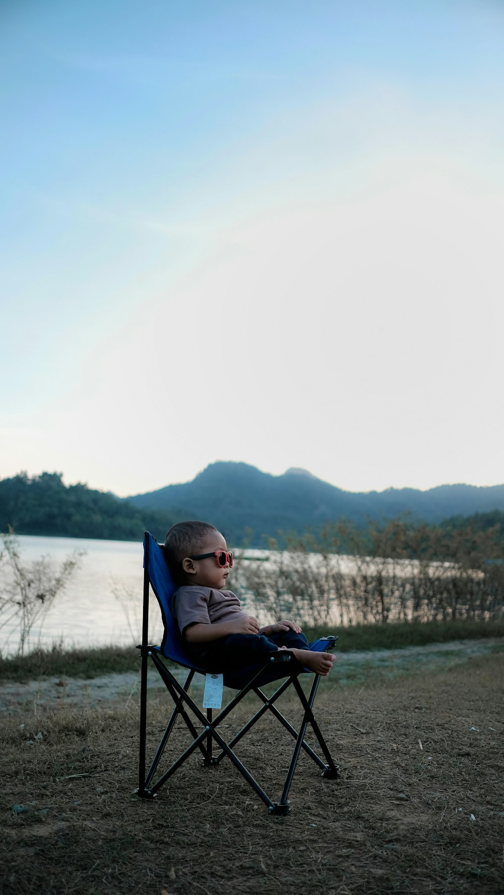 niño pequeño sentado en silla de camping negra y azul