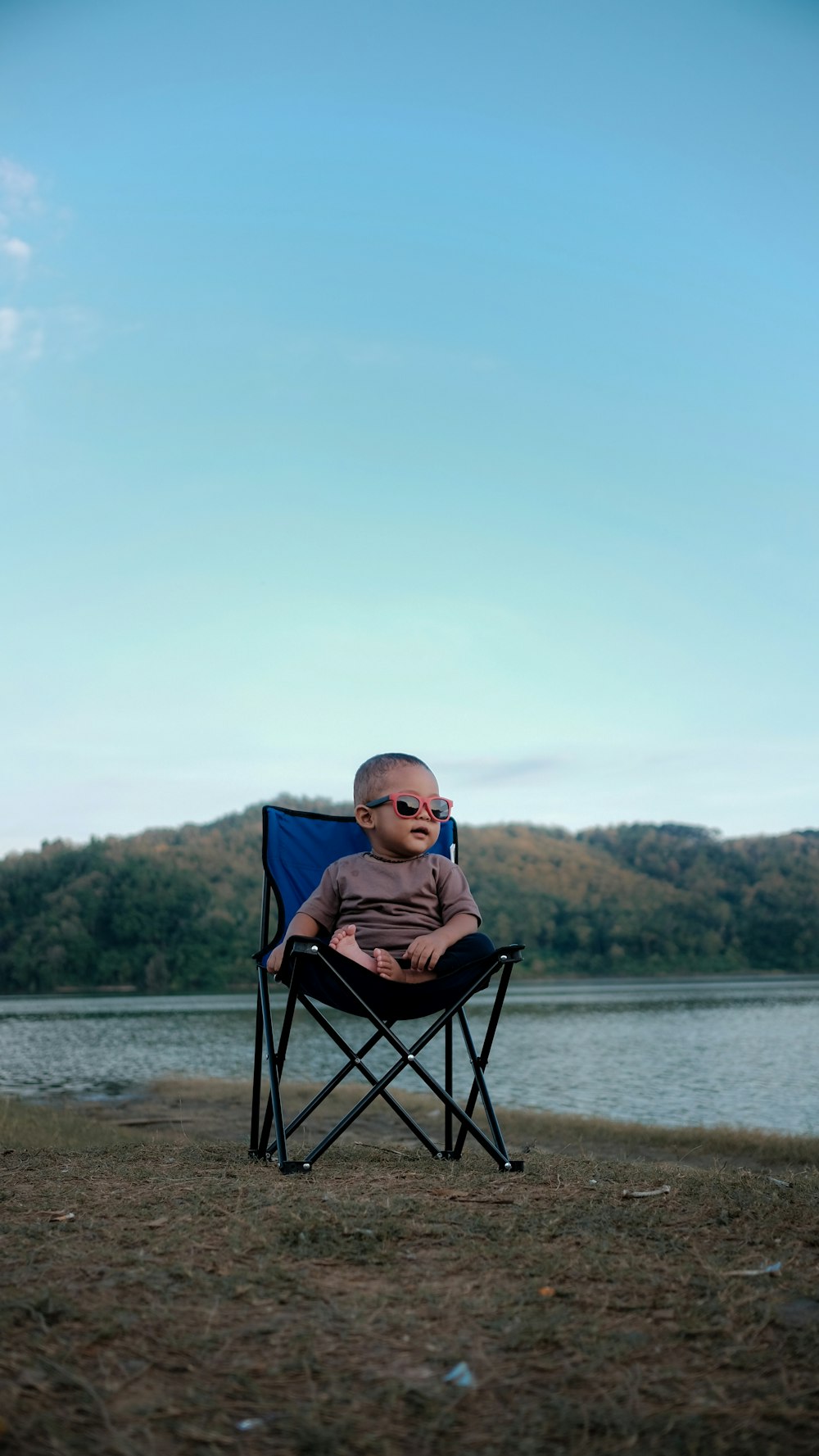 Junge sitzt auf blauem Campingstuhl Fotografie