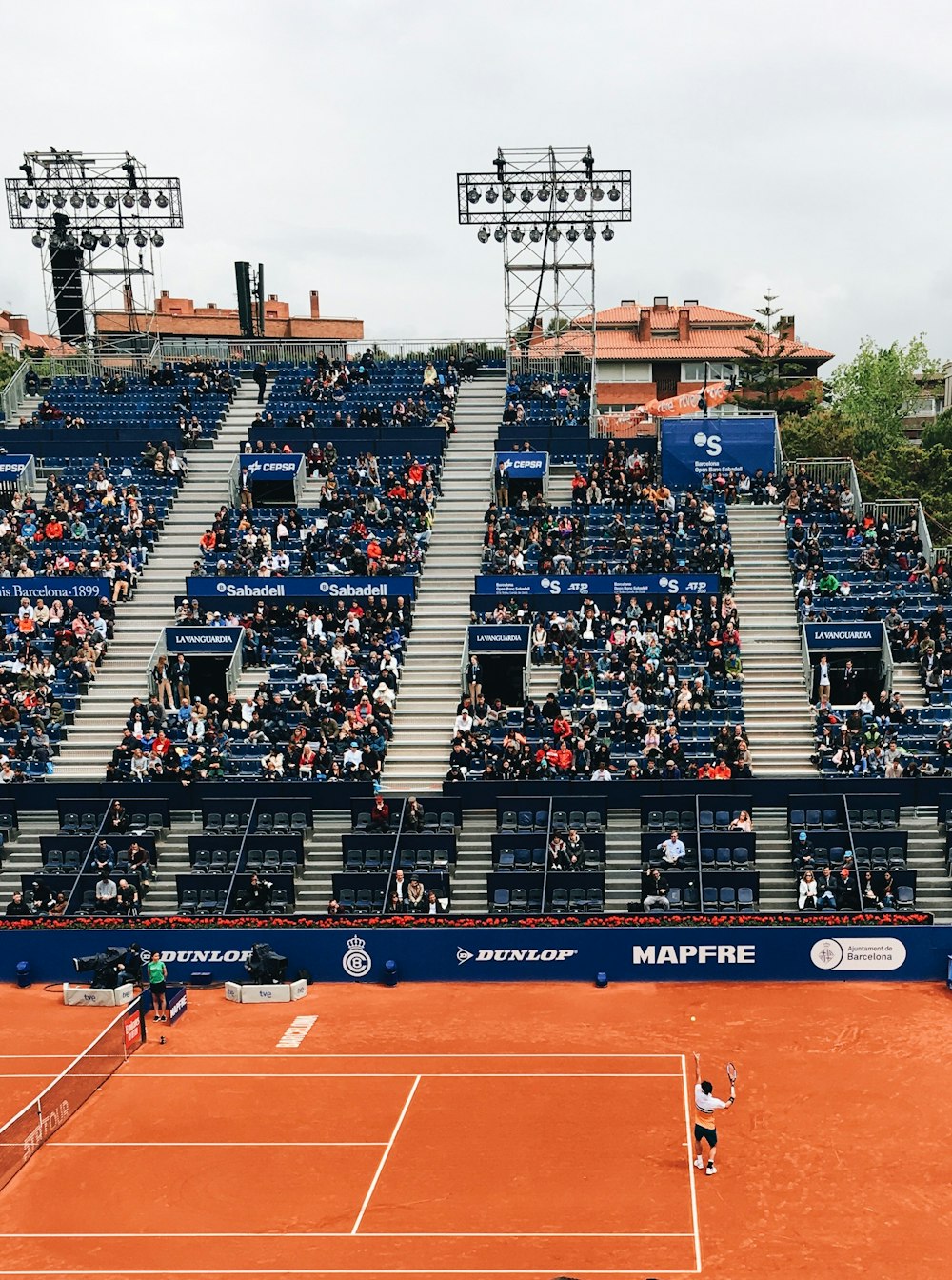 people sitting on bleachers while watching lawn tennis game during daytime