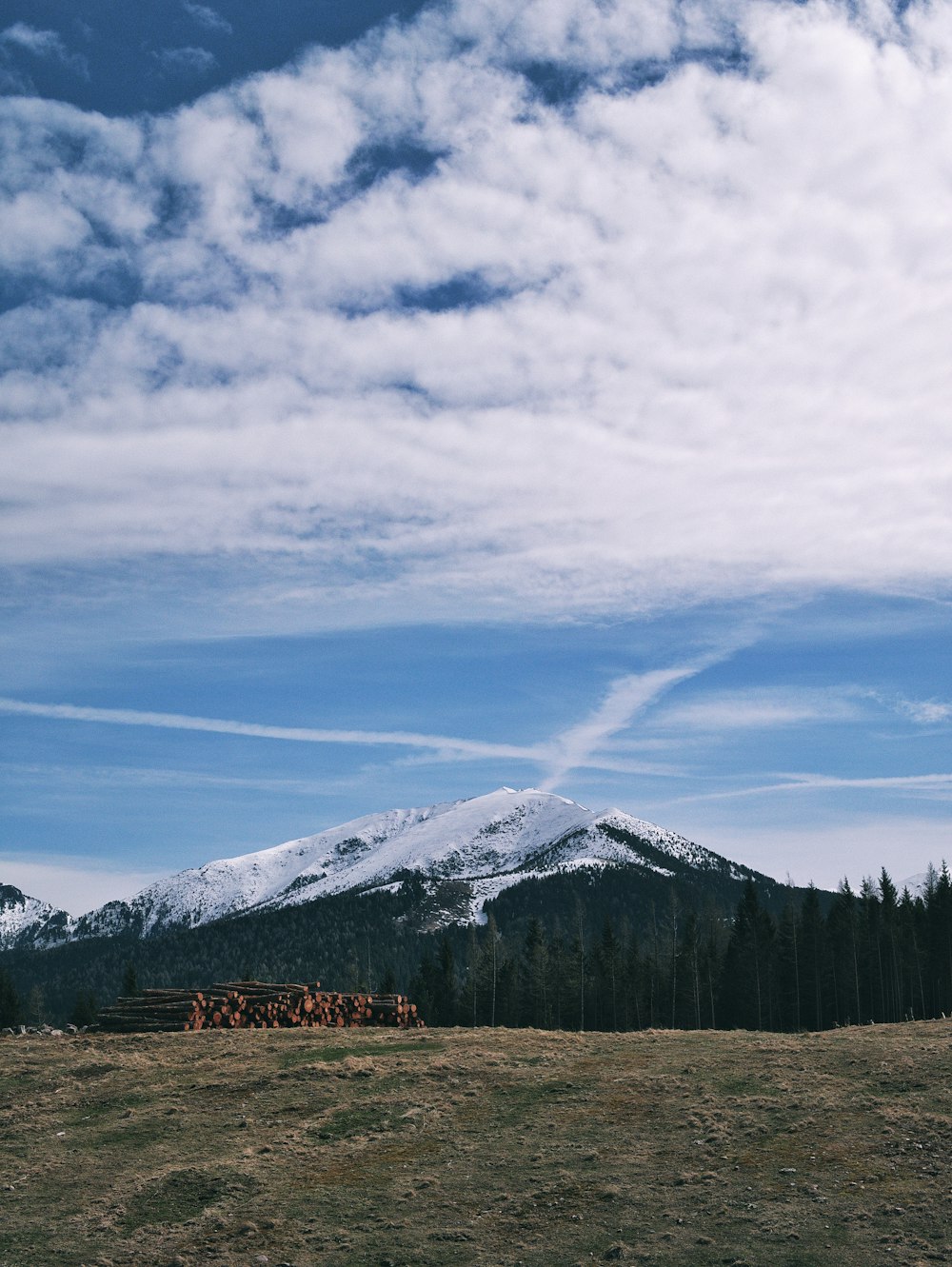 white cloudy sky over white snow capped hills across green grass field