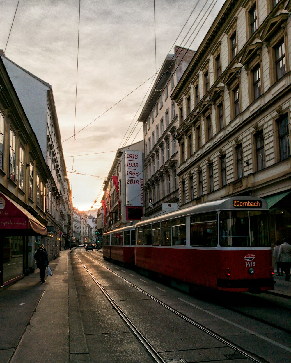 red and white train between building at daytime