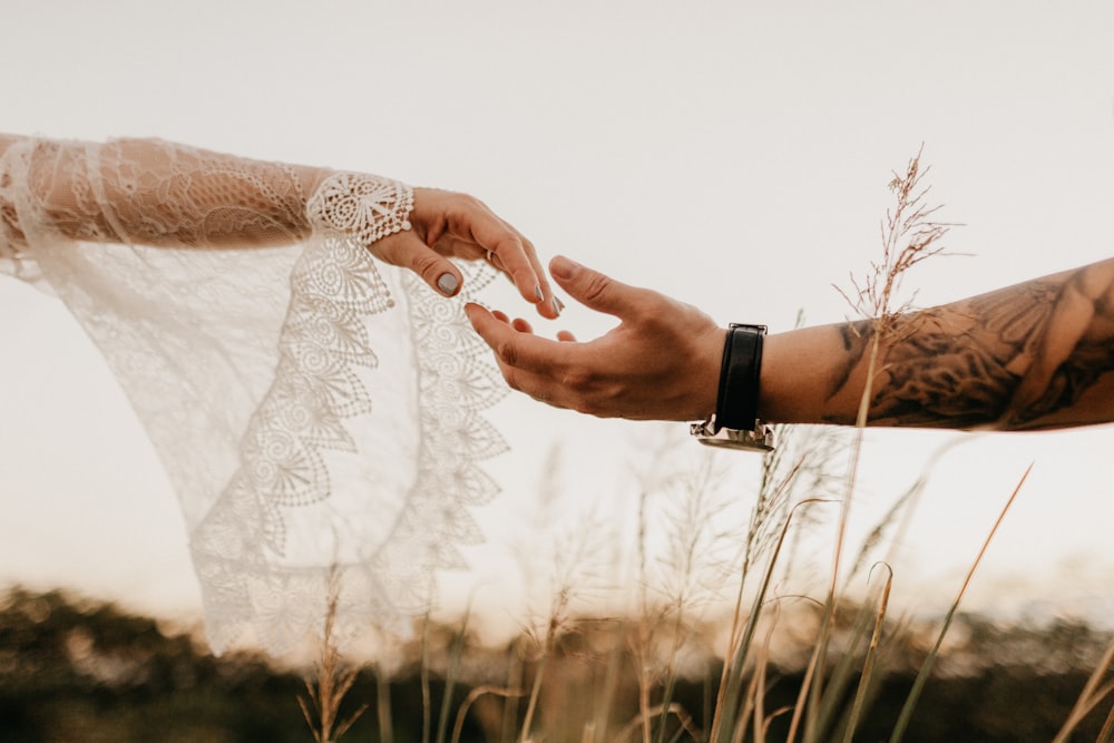 a bride and groom holding hands in a field