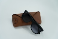 Elegant branded sunglasses placed against a soft white background emphasizing their premium design.