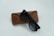 A pair of black sunglasses rests on a brown leather case, with the brand logo visible on both the sunglasses and the case. The setting is minimalistic, against a light background, emphasizing the sleek design of the eyewear and the texture of the case.