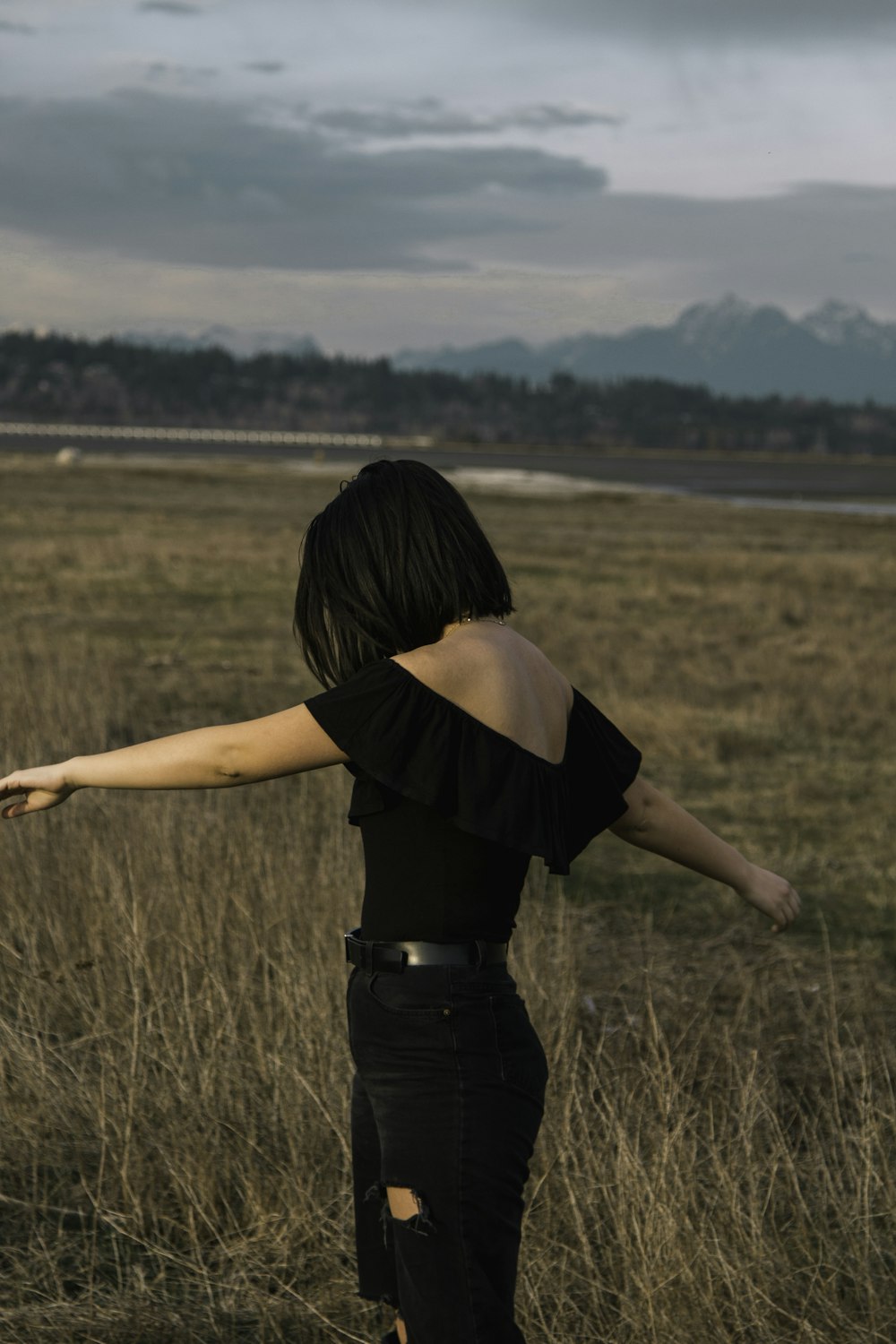 woman in black pants standing on brown field