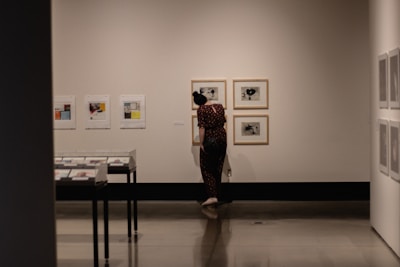 Close-up of a hand placing a framed artwork on a gallery wall.