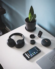 smartphone beside headphones and Google Home Mini