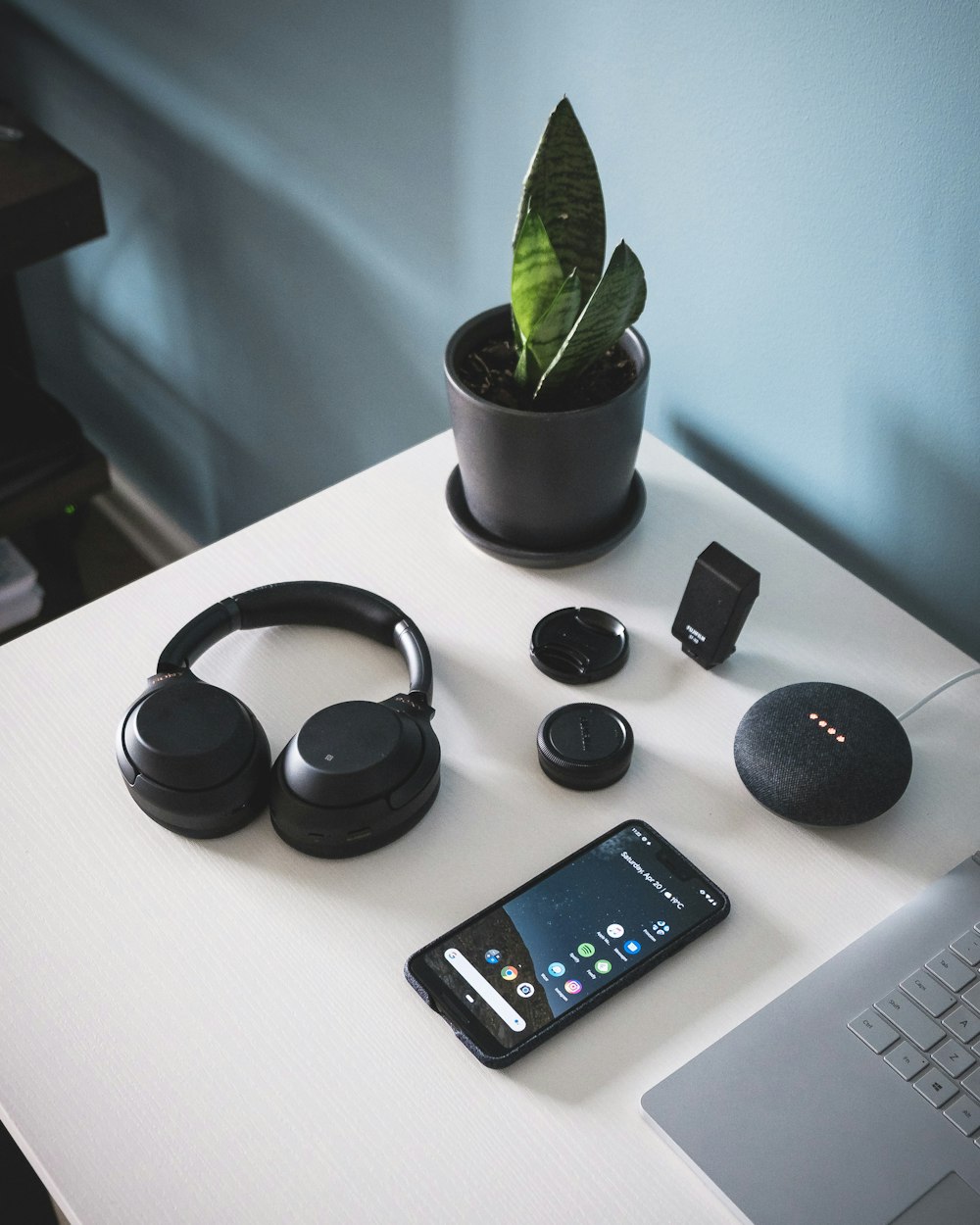 smartphone beside headphones and Google Home Mini
