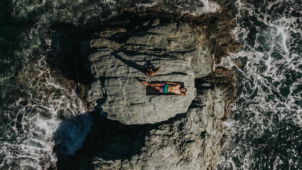 person lying on grey rock during daytime