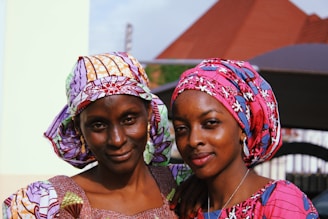 A man and woman smiling while wearing colorful scarves outdoors