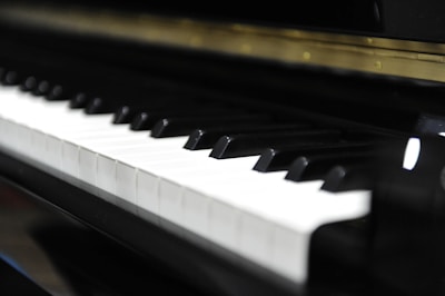 A close-up view of a piano keyboard, with both black and white keys clearly visible. The image captures the sheen on the keys, suggesting a well-maintained or new instrument.