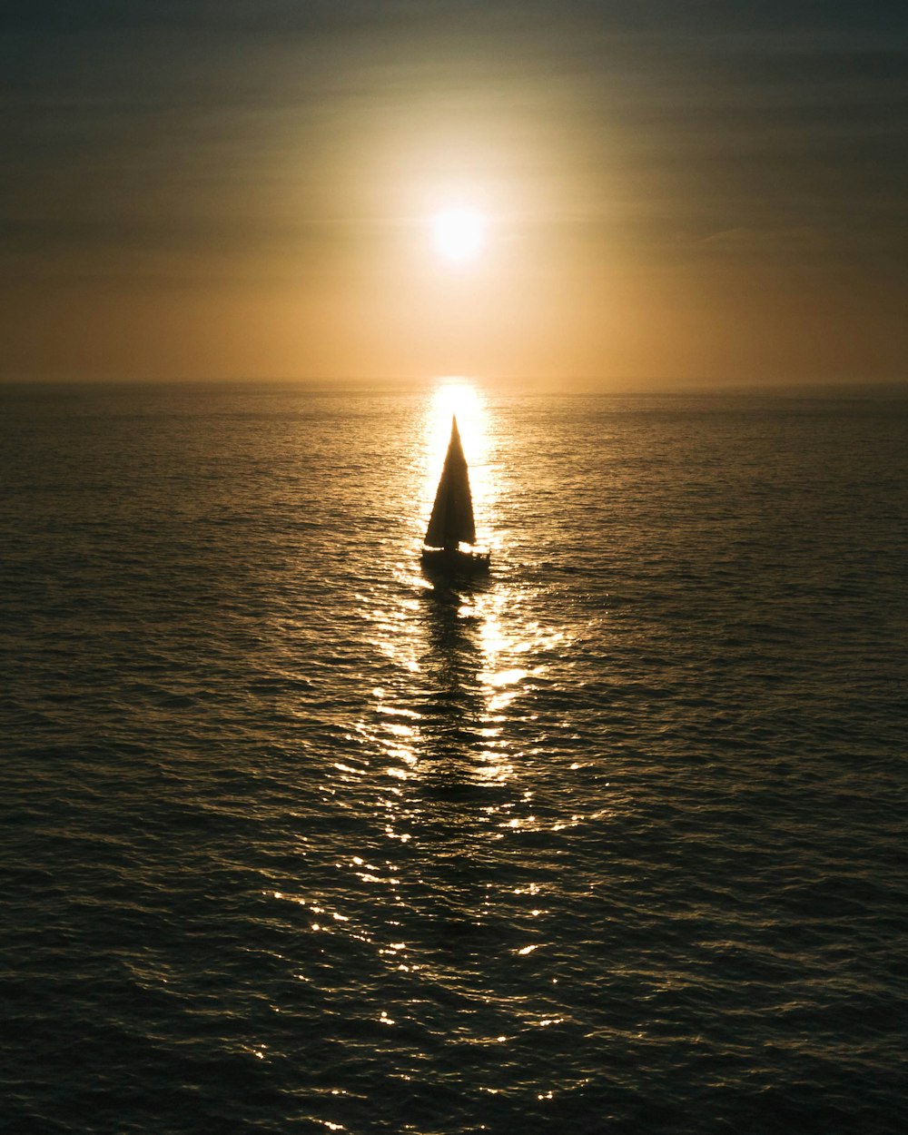 sailboat on calm body of water during golden hour