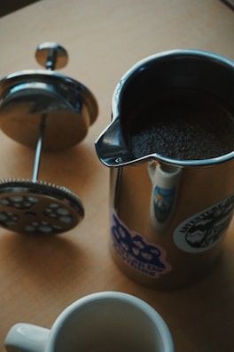 A stylish French press surrounded by coffee accessories.
