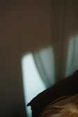 Soft morning light filtering through sheer curtains onto a cream linen bed.