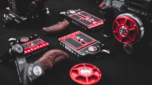 Various components and gears, featuring a range of intricate designs, are arranged on a dark surface. These items include detailed metal pieces with red and black color schemes, some with engraved patterns, suggesting they are parts of high-end equipment.