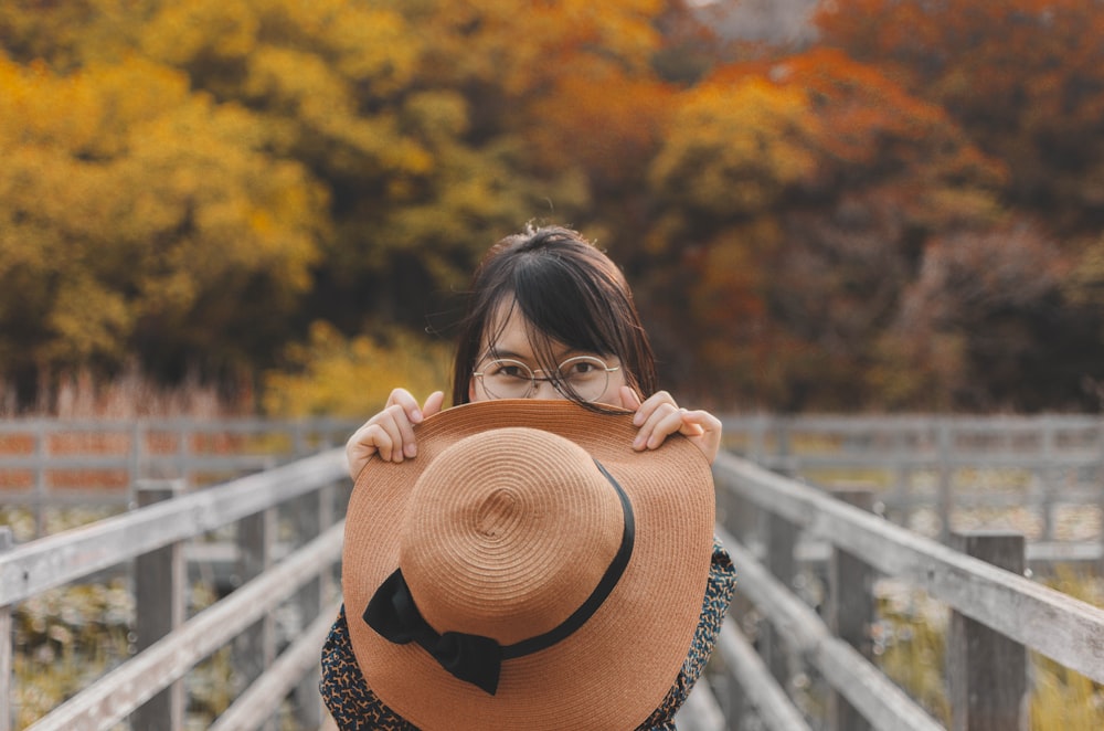 woman holding brown hat in front of face