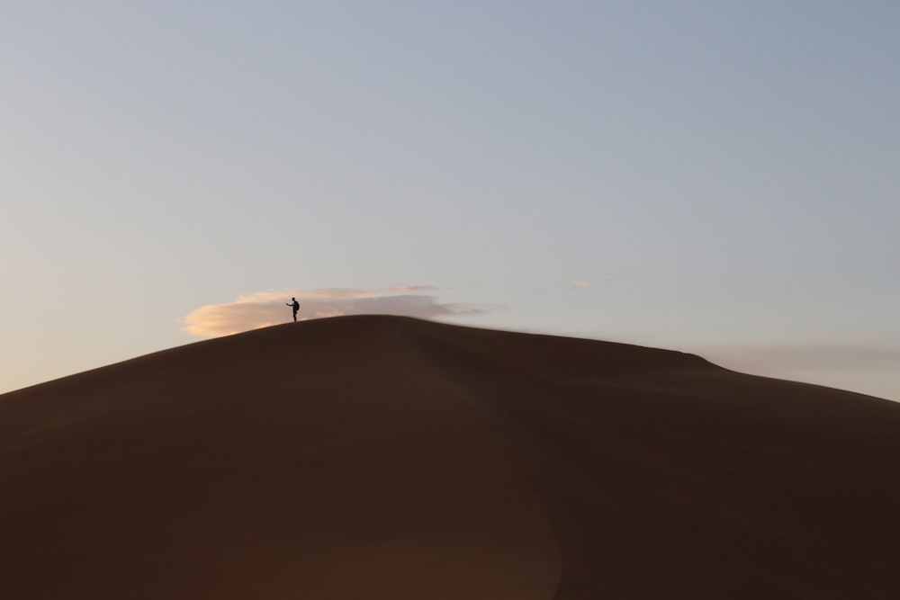 person standing on brown sand mountain