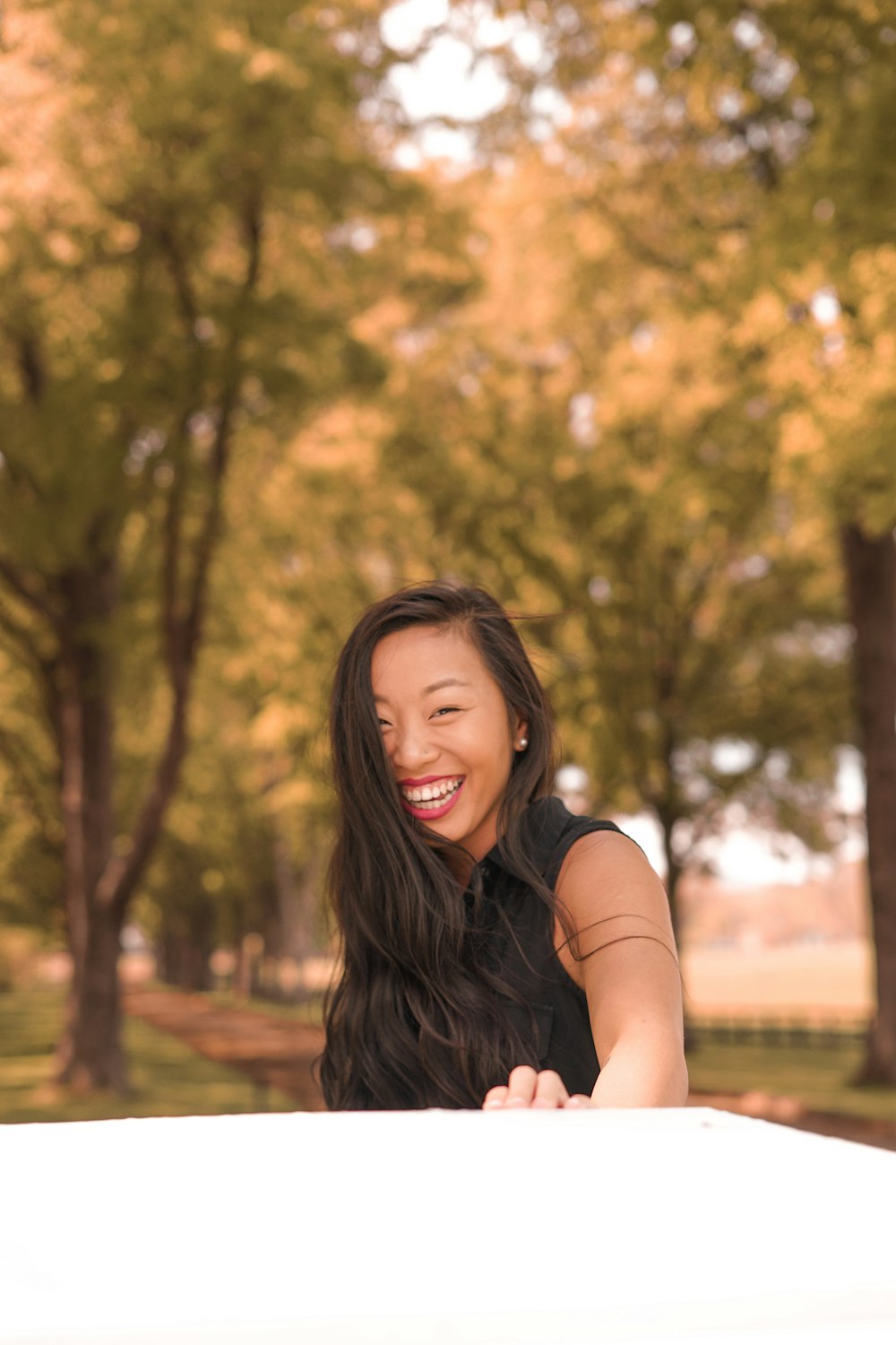 smiling woman wearing black top standing near trees