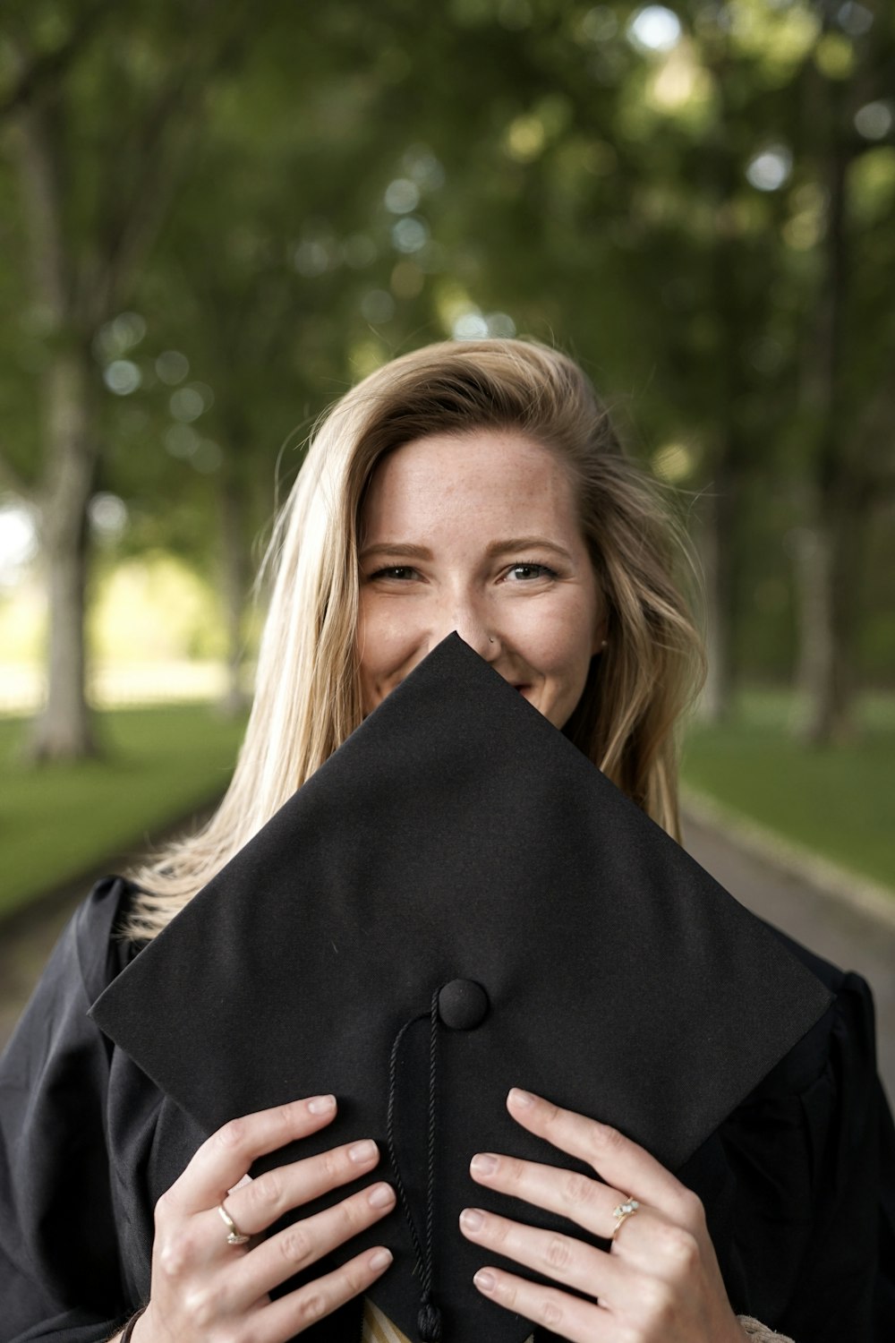 smiling woman slightly covering face with mortar board