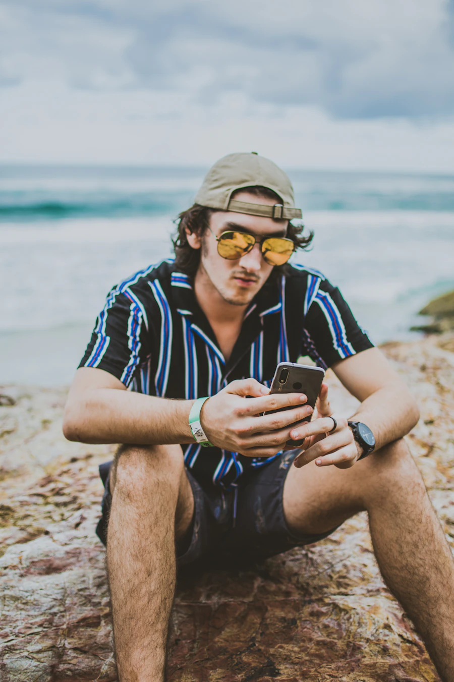 Person checking a phone near the water's edge at the beach