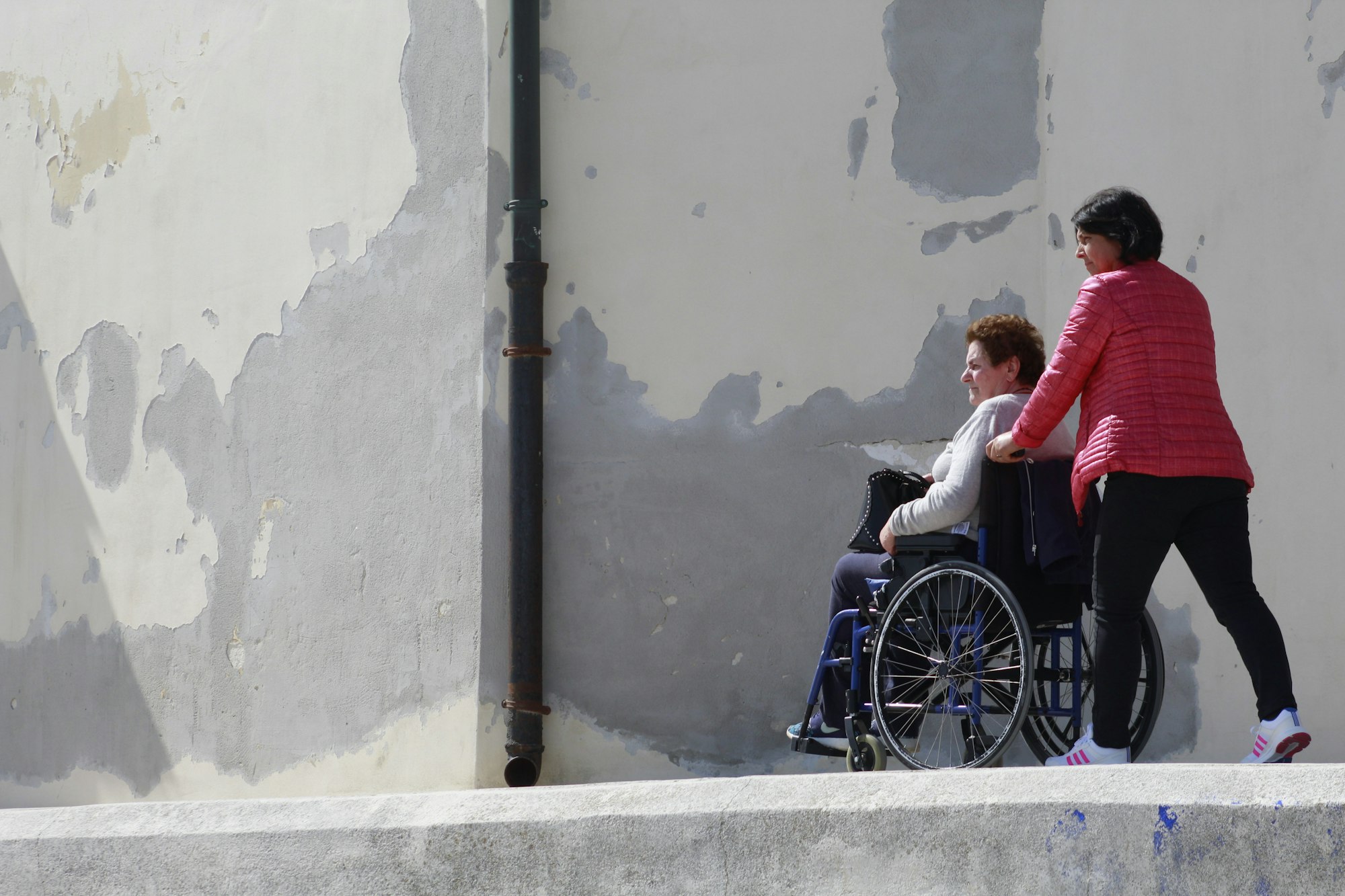 Lady pushing another lady in a wheelchair