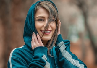 smiling woman wearing blue hoodie in selective focus photography