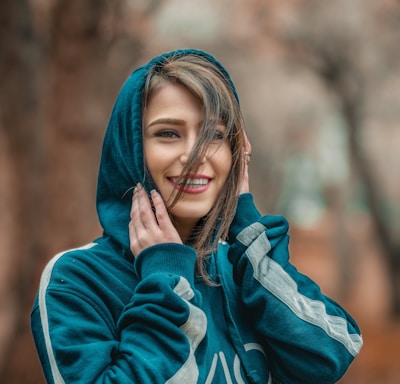 smiling woman wearing blue hoodie in selective focus photography