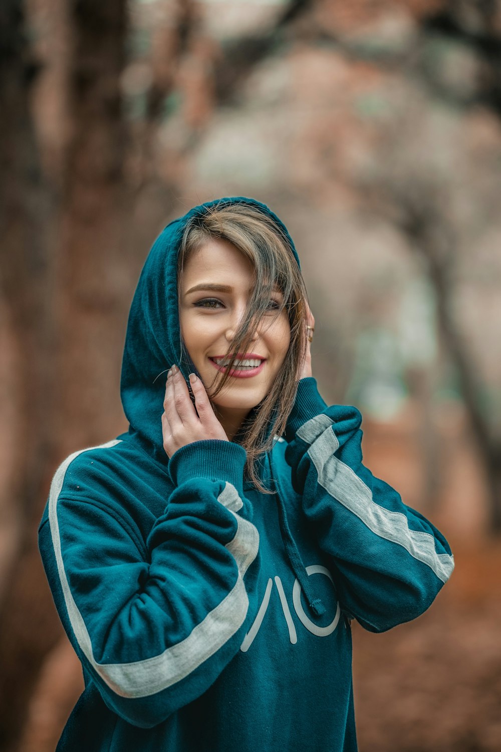Mujer sonriente con sudadera con capucha azul en fotografía de enfoque selectivo