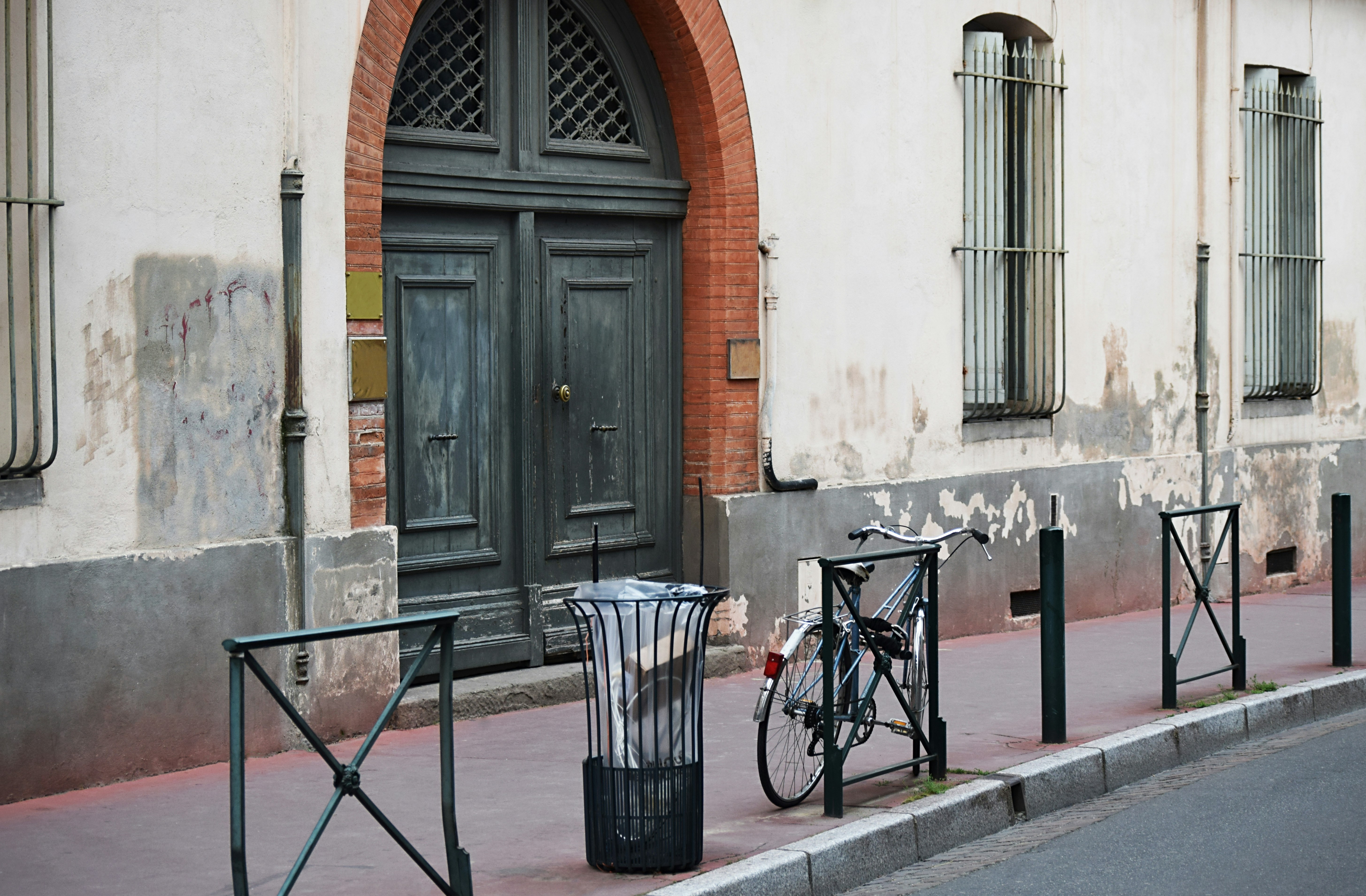 Cubo de basura negro al lado de la bicicleta azul