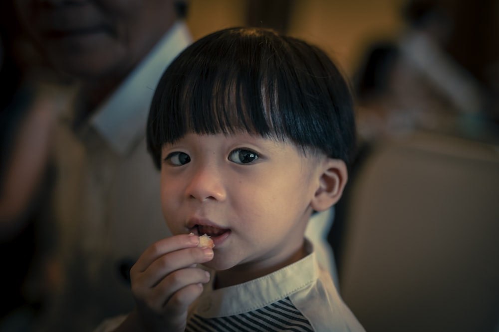 boy wearing white shirt holding food