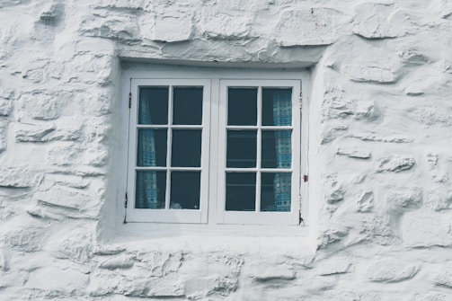 Window dressed with custom-made blue curtains and sleek blinds, highlighting craftsmanship.