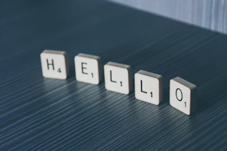 white Hello scrabble tiles on gray wooden surface