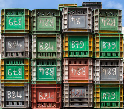 A row of colorful plastic and metal containers lined up outdoors against a clear sky.