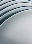 A close-up view of overlapping ceramic plates with smooth surfaces, creating a pattern of curved lines and shadows.