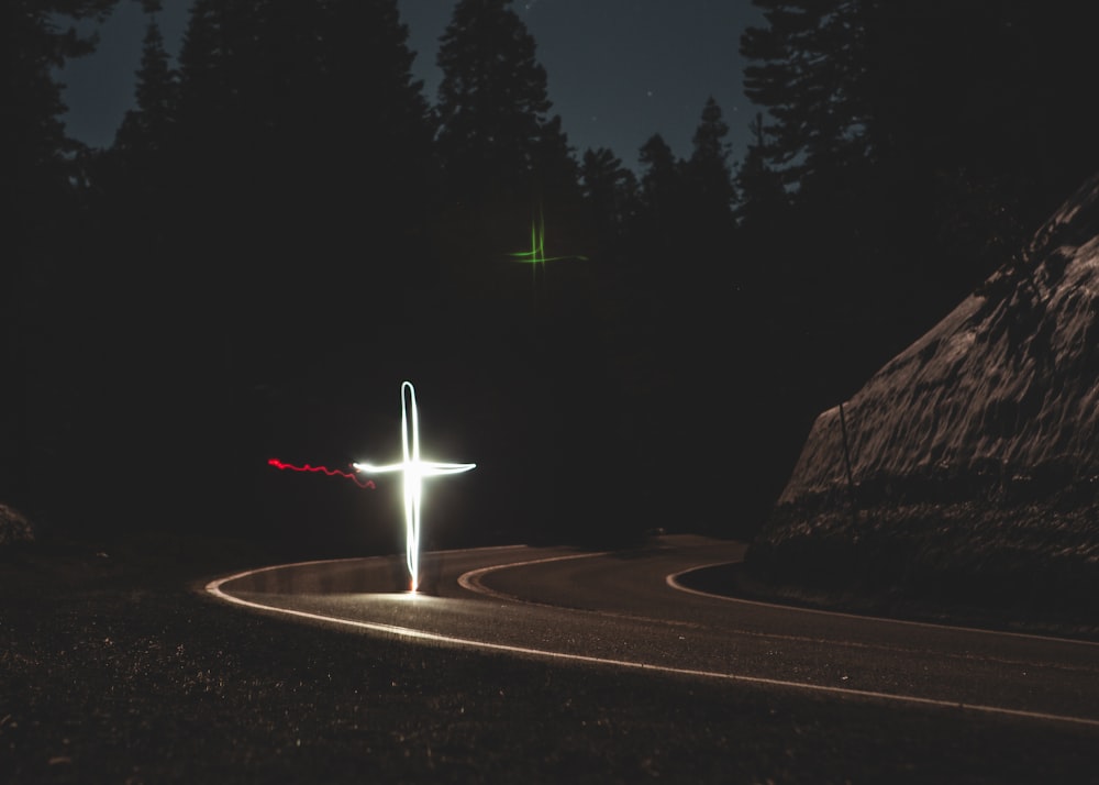 luce bianca a forma di croce sulla strada durante la notte