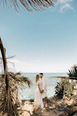 Couple enjoying a romantic dinner overlooking the sea at a tropical resort.