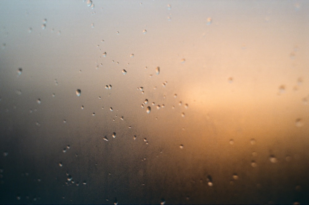 rain drops on a window with a sunset in the background